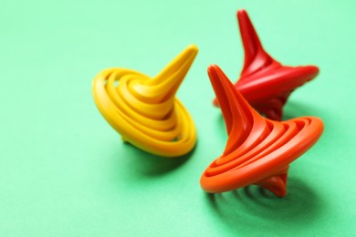 Many colorful spinning tops on green background, closeup. Space for text