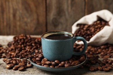 Photo of Cup of aromatic coffee and beans on wooden table