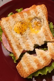 Cute monster sandwich with fried eggs on burgundy plate, top view. Halloween snack