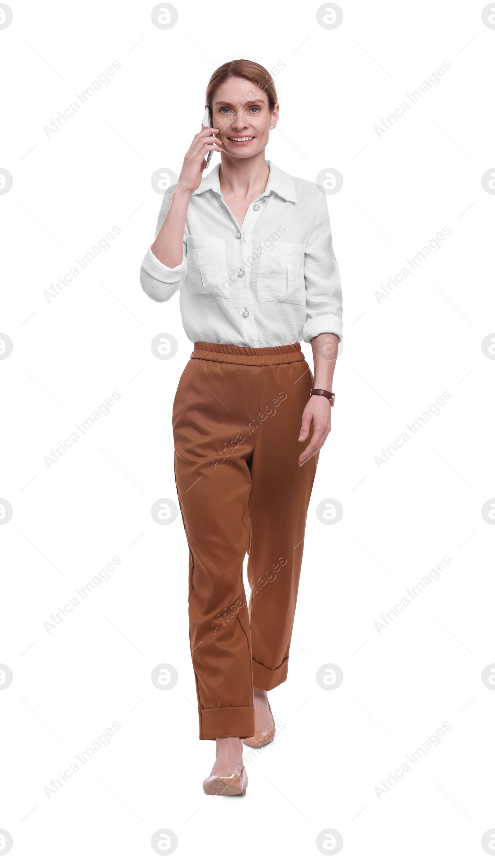 Photo of Beautiful happy businesswoman talking on smartphone while walking against white background