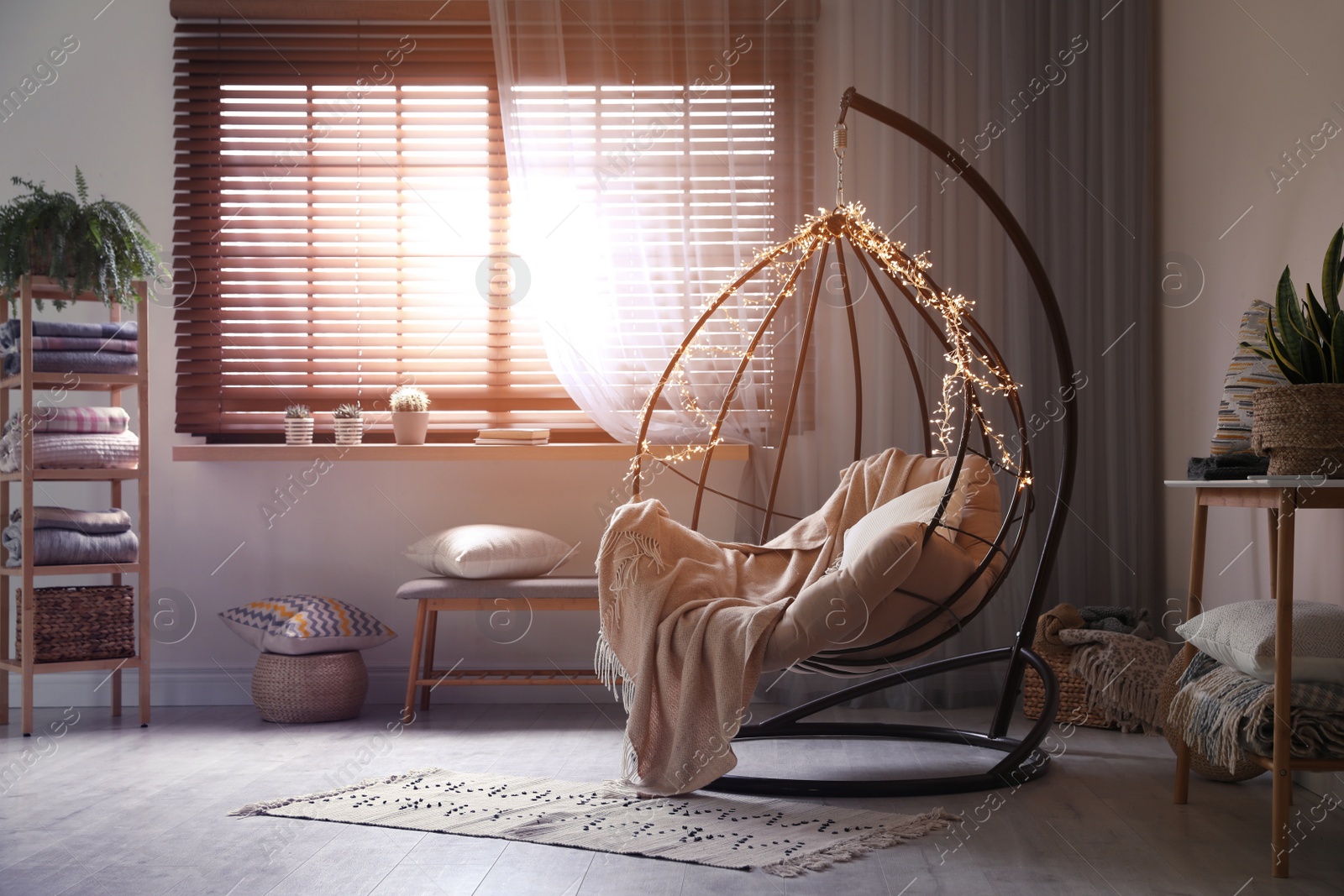 Photo of Cozy hanging chair with fairy lights in modern living room. Interior design