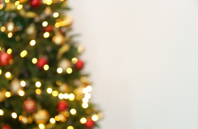 Blurred view of Christmas tree with fairy lights on white background