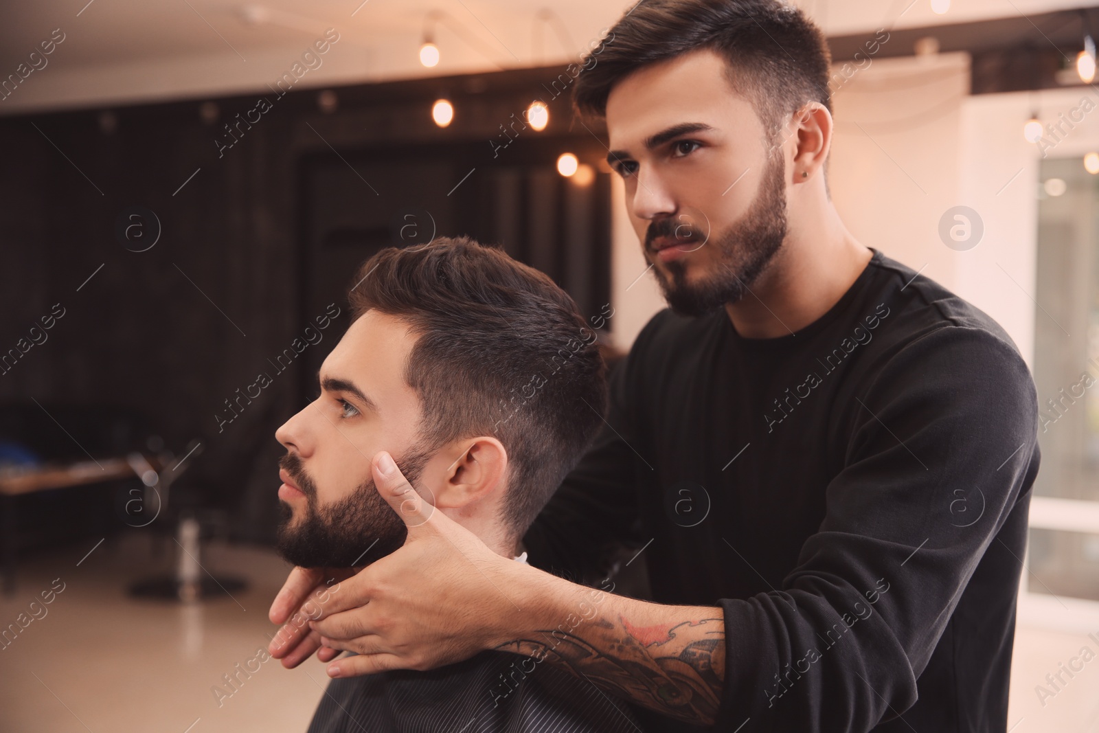 Photo of Hairdresser applying serum onto client's beard in barbershop. Professional shaving service