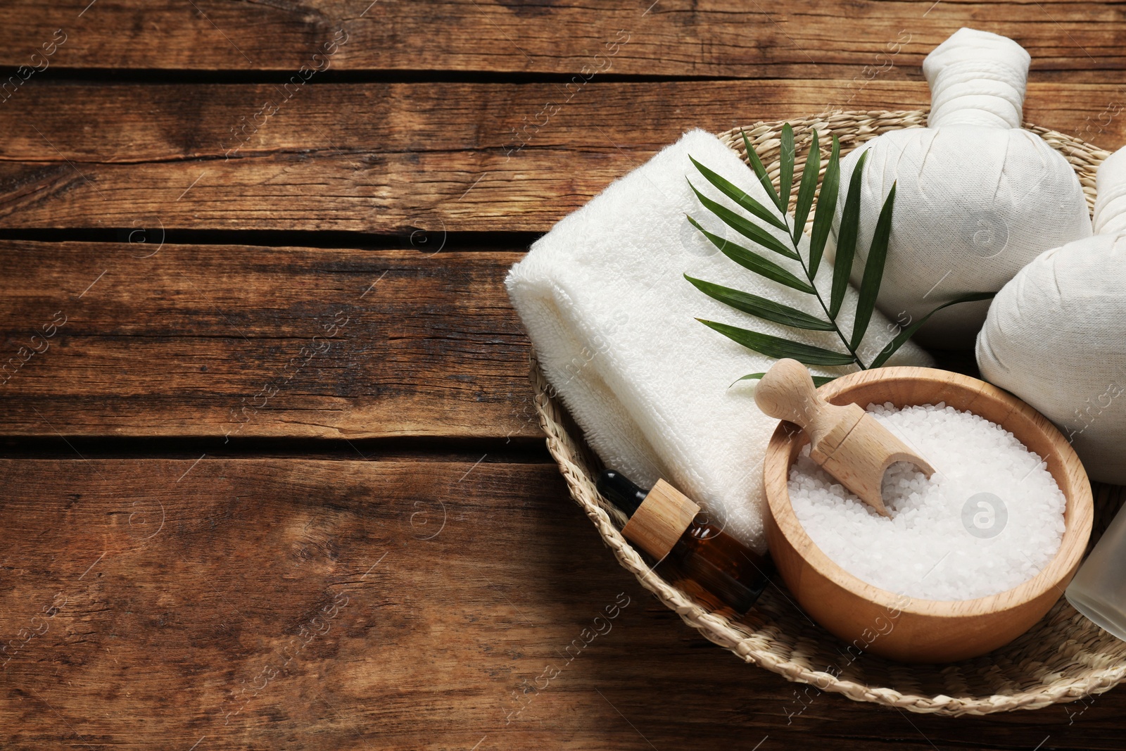 Photo of Composition with herbal massage bags and other spa products on wooden table. Space for text