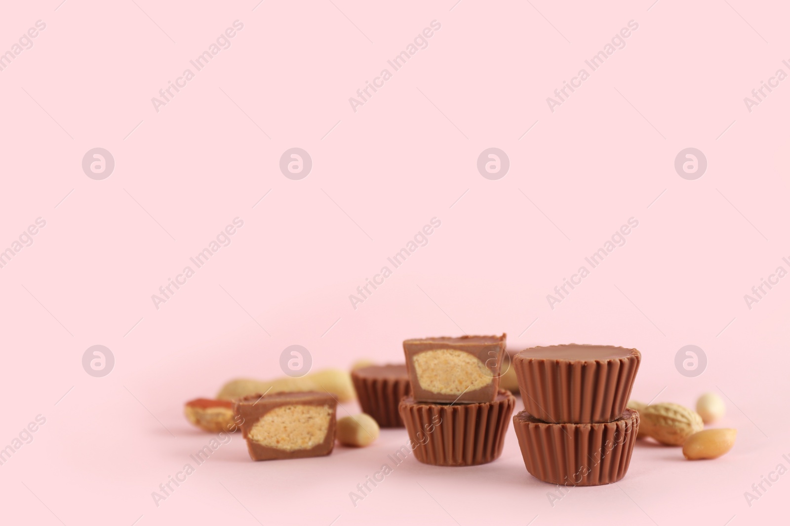 Photo of Sweet peanut butter cups on pink background. Space for text