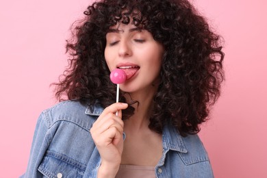 Beautiful woman with lollipop on pink background