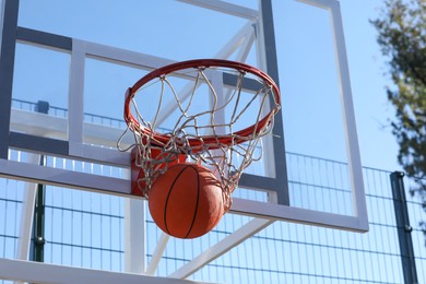 Basketball ball and hoop with net outdoors on sunny day