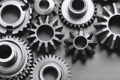 Photo of Many different stainless steel gears on grey background, above view