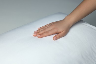 Photo of Woman touching soft white pillow on bed, closeup