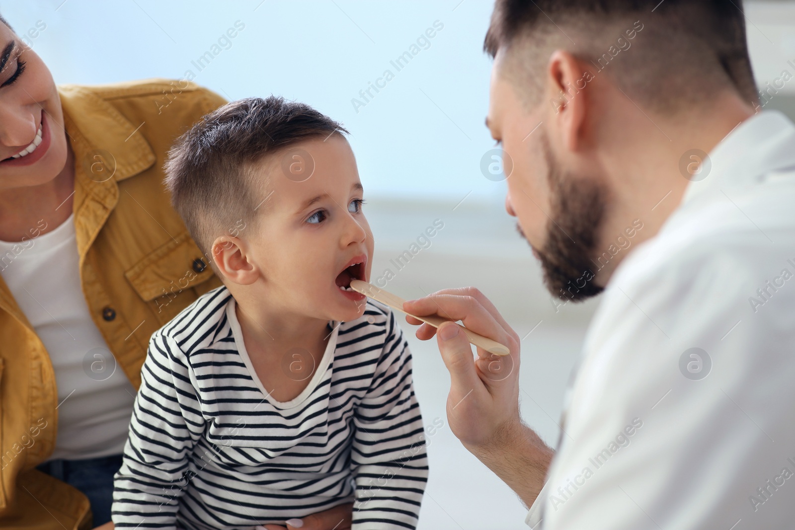 Photo of Mother and son visiting pediatrician in hospital. Doctor examining little boy