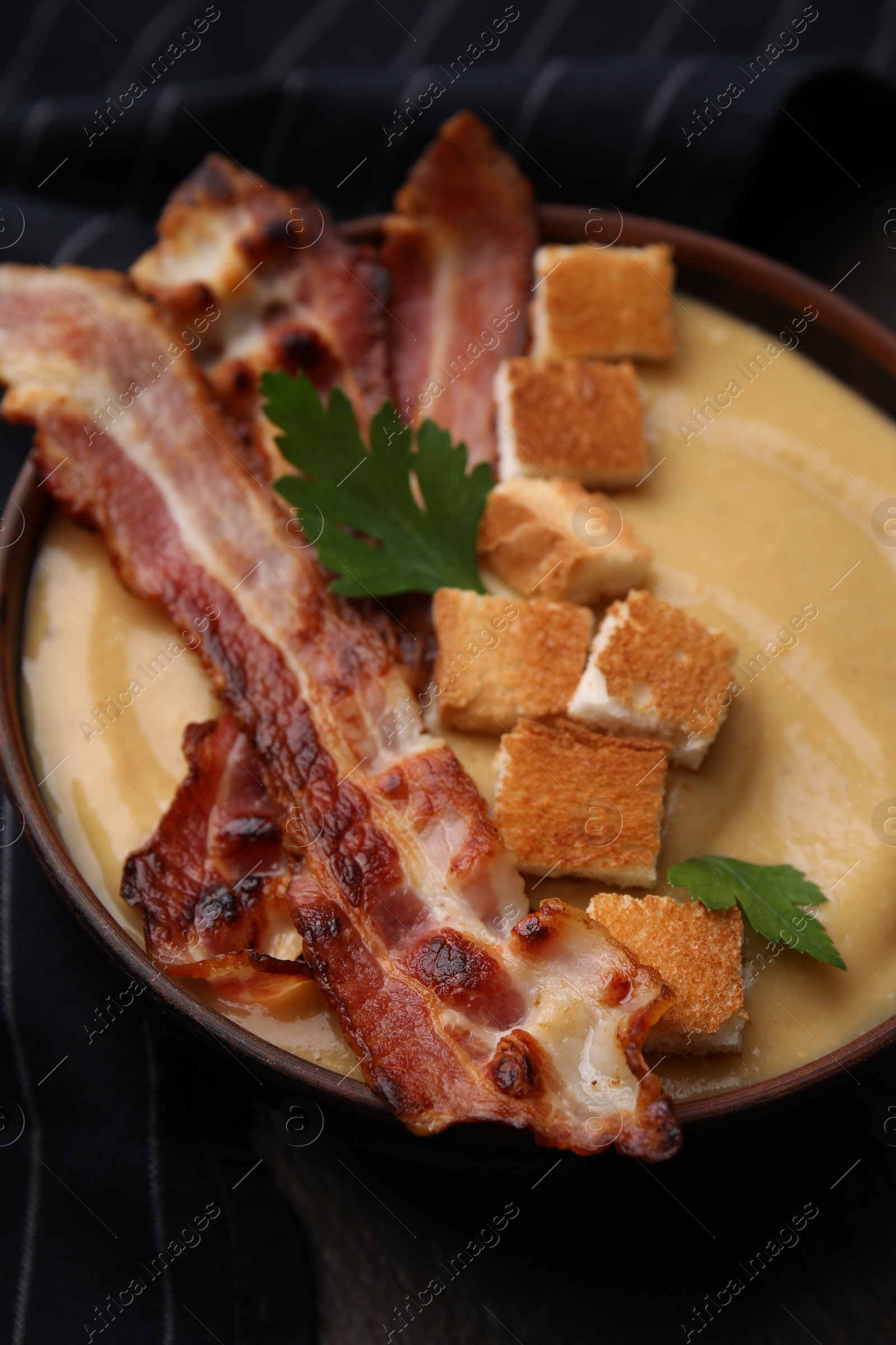 Photo of Delicious lentil soup with bacon and parsley in bowl on table, closeup