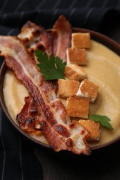 Photo of Delicious lentil soup with bacon and parsley in bowl on table, closeup