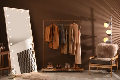 Stylish mirror with light bulbs and comfortable armchair in dressing room. Interior design