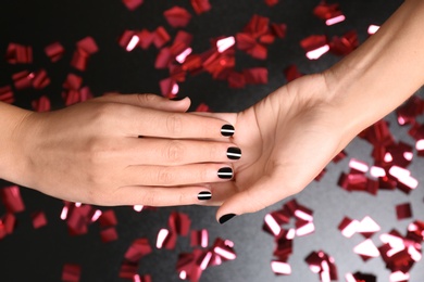 Photo of Woman with black manicure on dark background, closeup. Nail polish trends