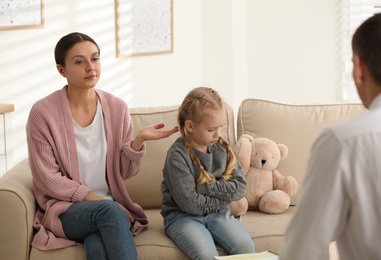 Photo of Little girl and her mother on appointment with child psychotherapist indoors