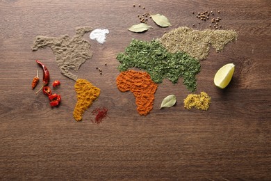 World map of different spices on wooden table, flat lay