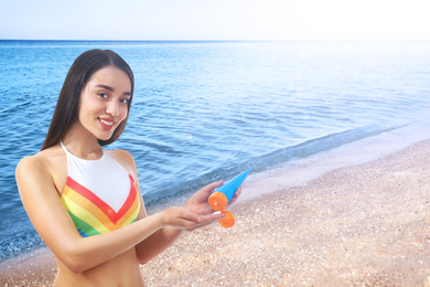 Young woman applying sun protection cream at beach, space for text