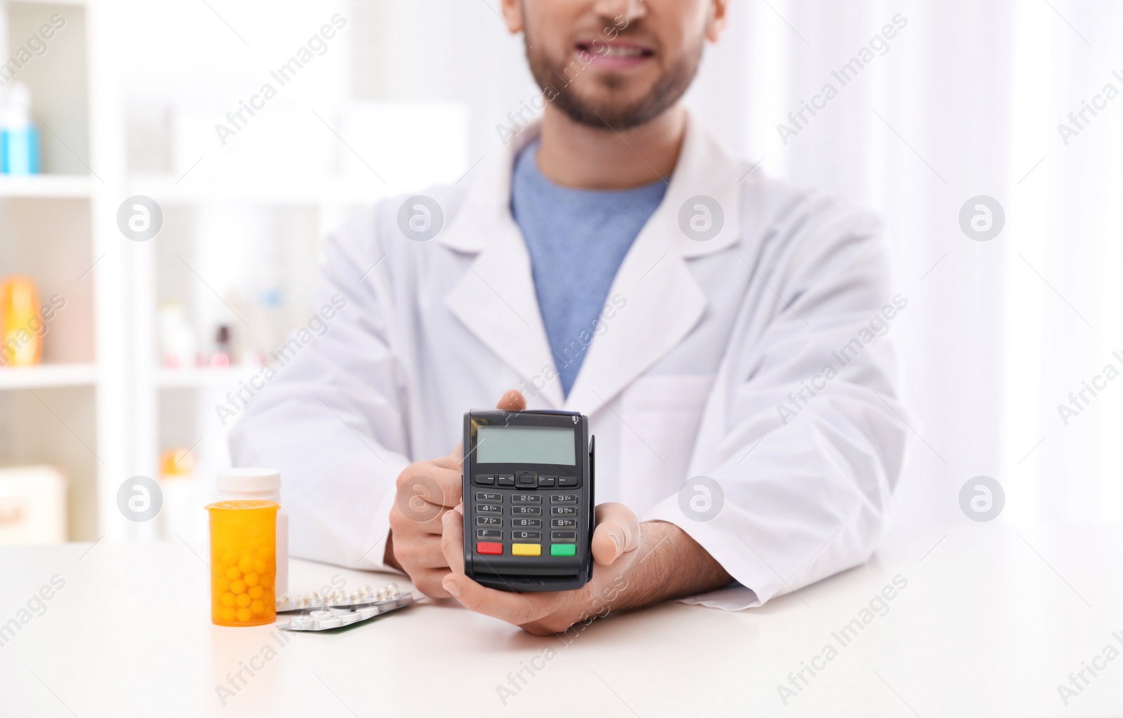 Photo of Pharmacist with payment terminal and pills in drug store, closeup