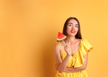 Beautiful young woman posing with watermelon on color background