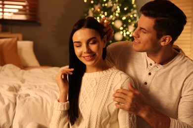 Photo of Happy couple in festively decorated bedroom. Christmas celebration