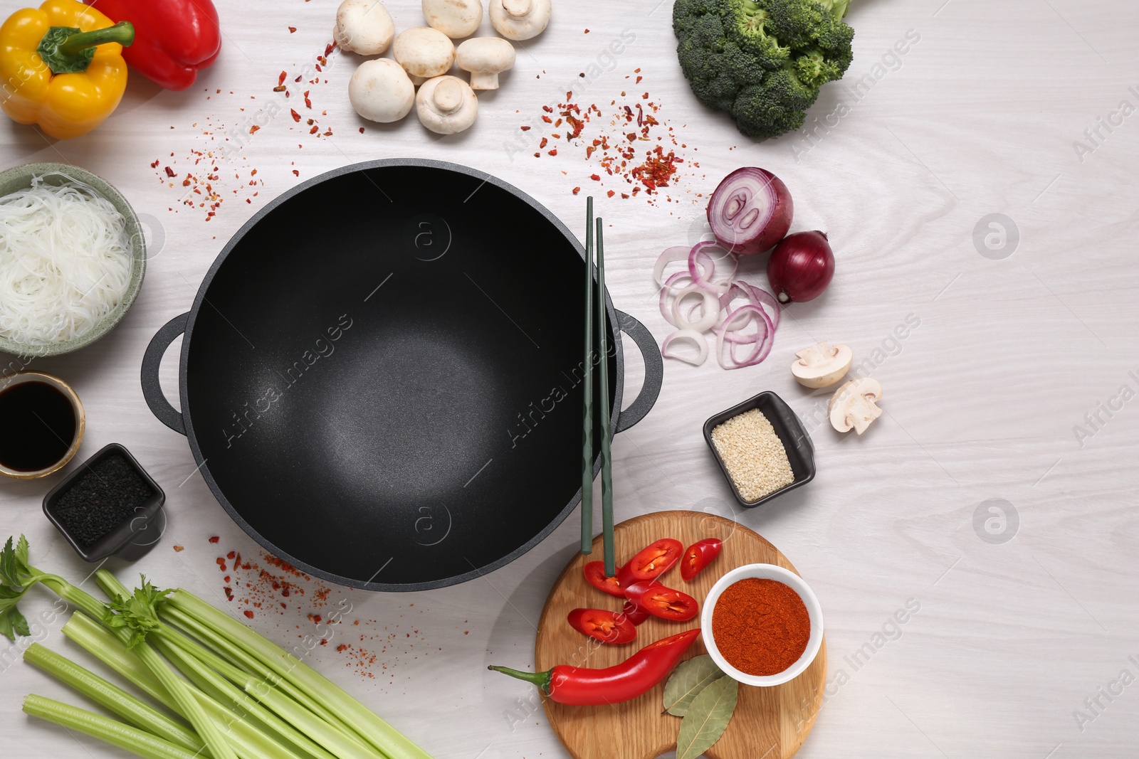 Photo of Wok, chopsticks and different products on white wooden table, flat lay. Space for text