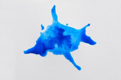 Blot of light blue ink on white background, top view