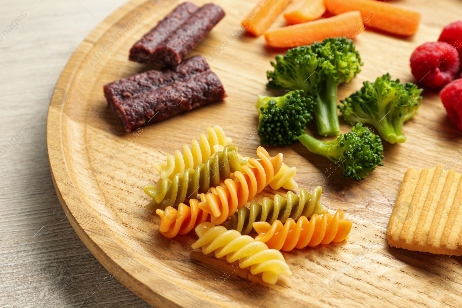 Photo of Wooden board with different finger foods for baby on table, closeup