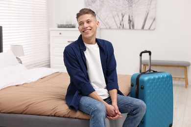 Smiling guest relaxing on bed in stylish hotel room