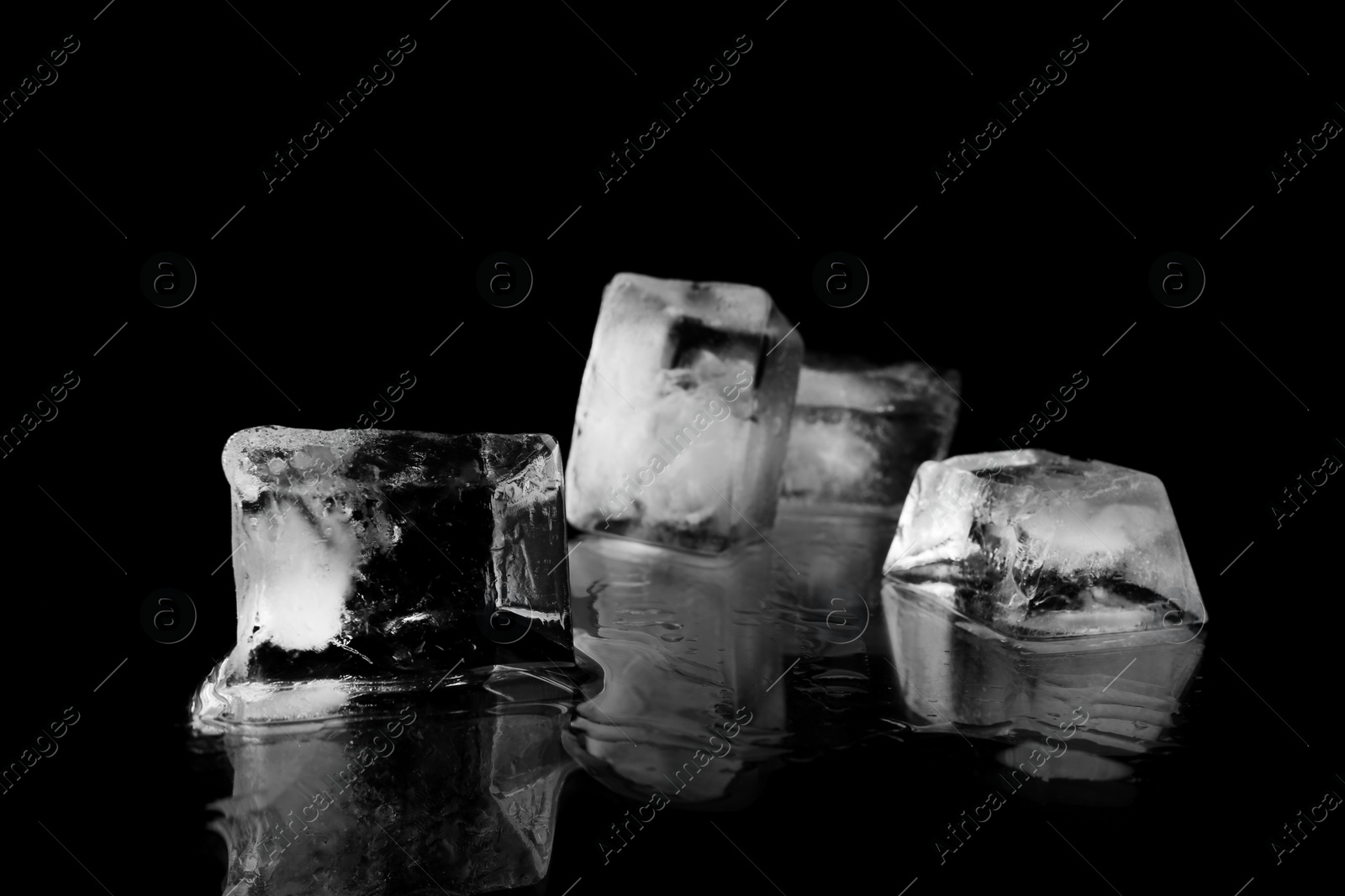 Photo of Transparent ice cubes on black mirror surface