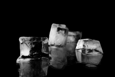 Photo of Transparent ice cubes on black mirror surface