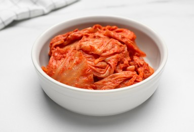 Photo of Bowl of spicy cabbage kimchi on white marble table