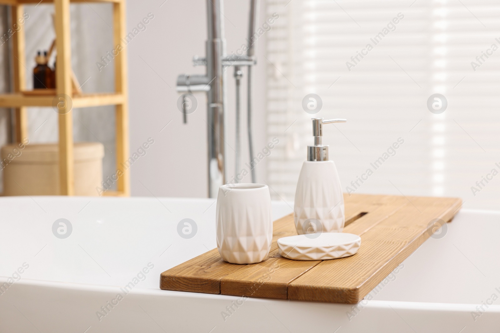 Photo of Set of bath accessories on tub in bathroom