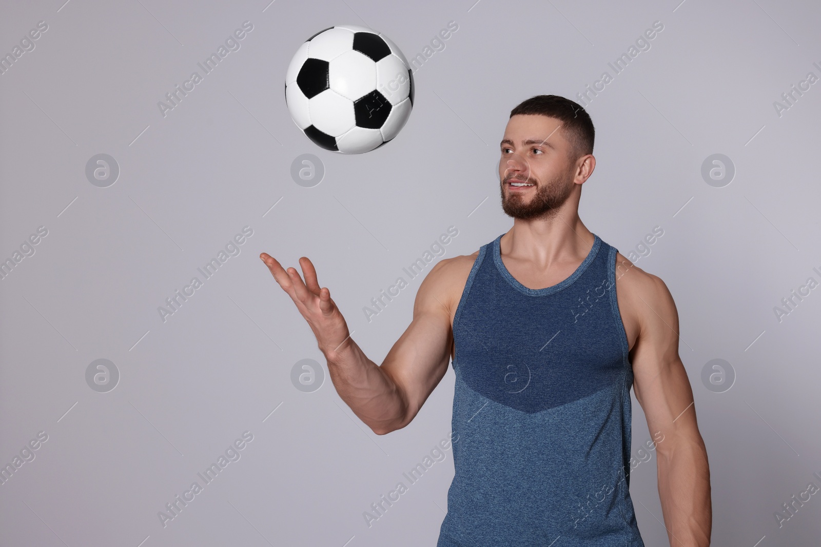 Photo of Athletic young man with soccer ball on light grey background. Space for text