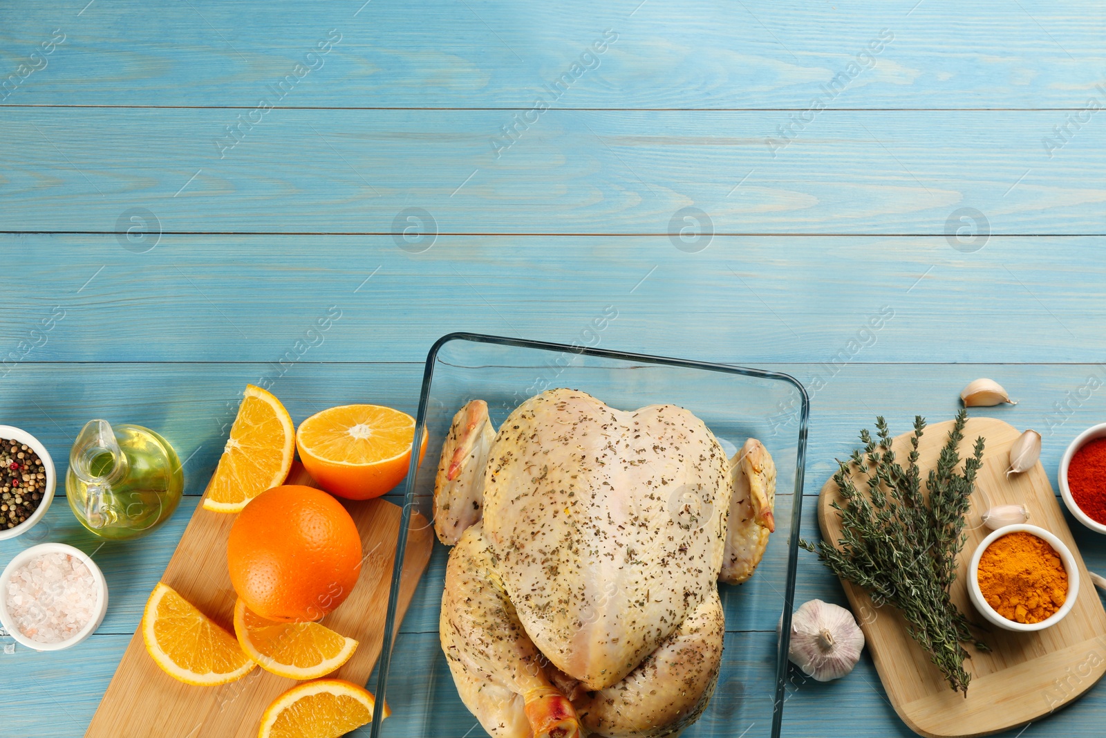 Photo of Raw chicken, orange slices and other ingredients on light blue wooden table, flat lay. Space for text