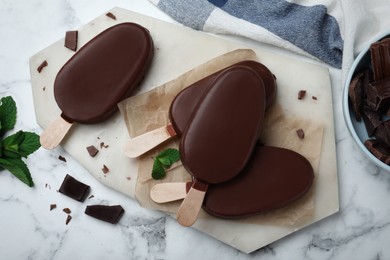 Photo of Delicious glazed ice cream bars with mint and chocolate on white marble table, flat lay