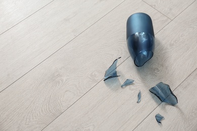 Photo of Broken blue glass vase on wooden floor. Space for text