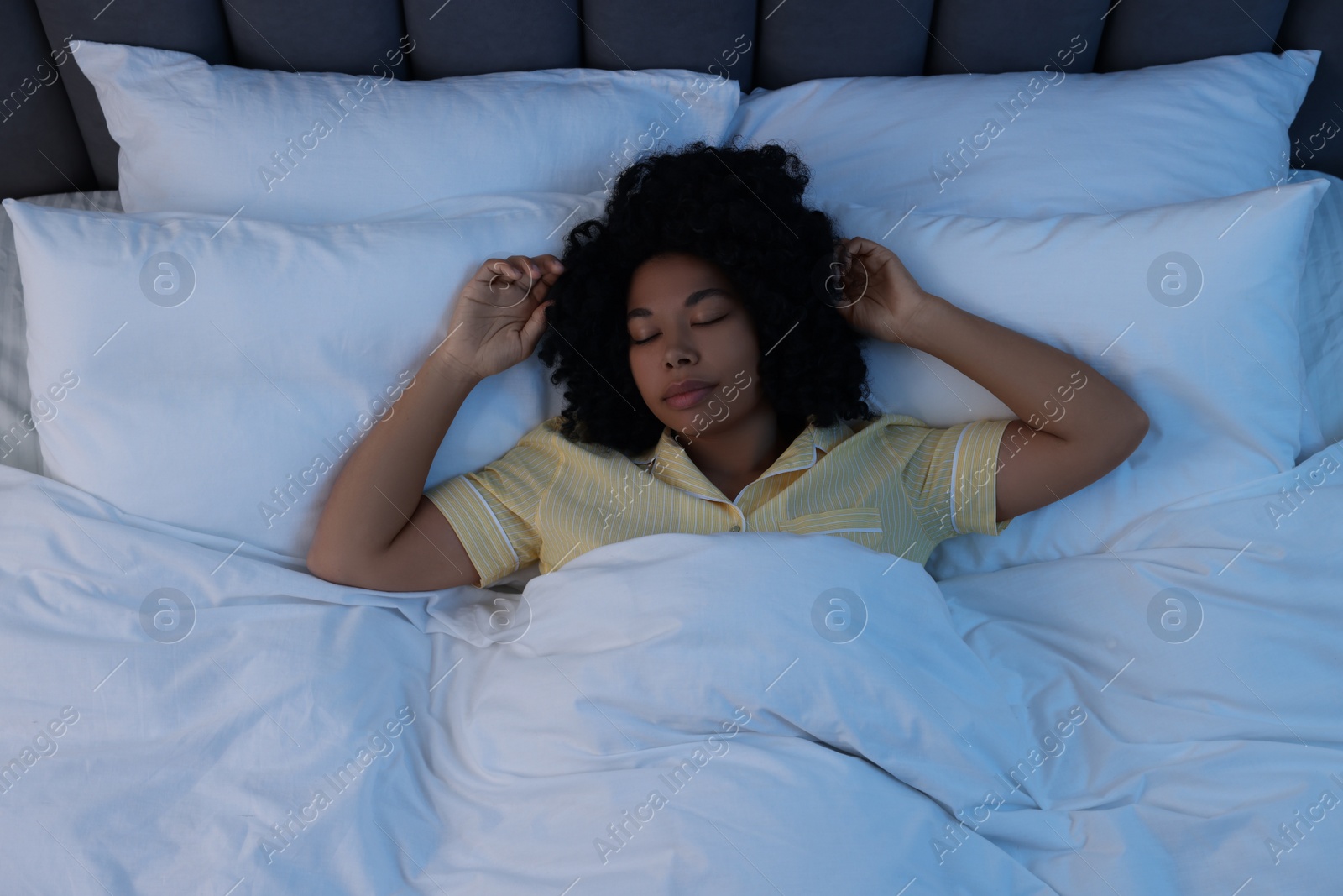 Photo of Young woman sleeping in soft bed at night, above view