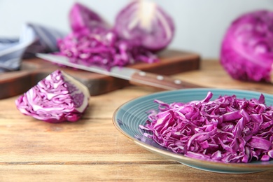 Photo of Shredded red cabbage on wooden table, closeup