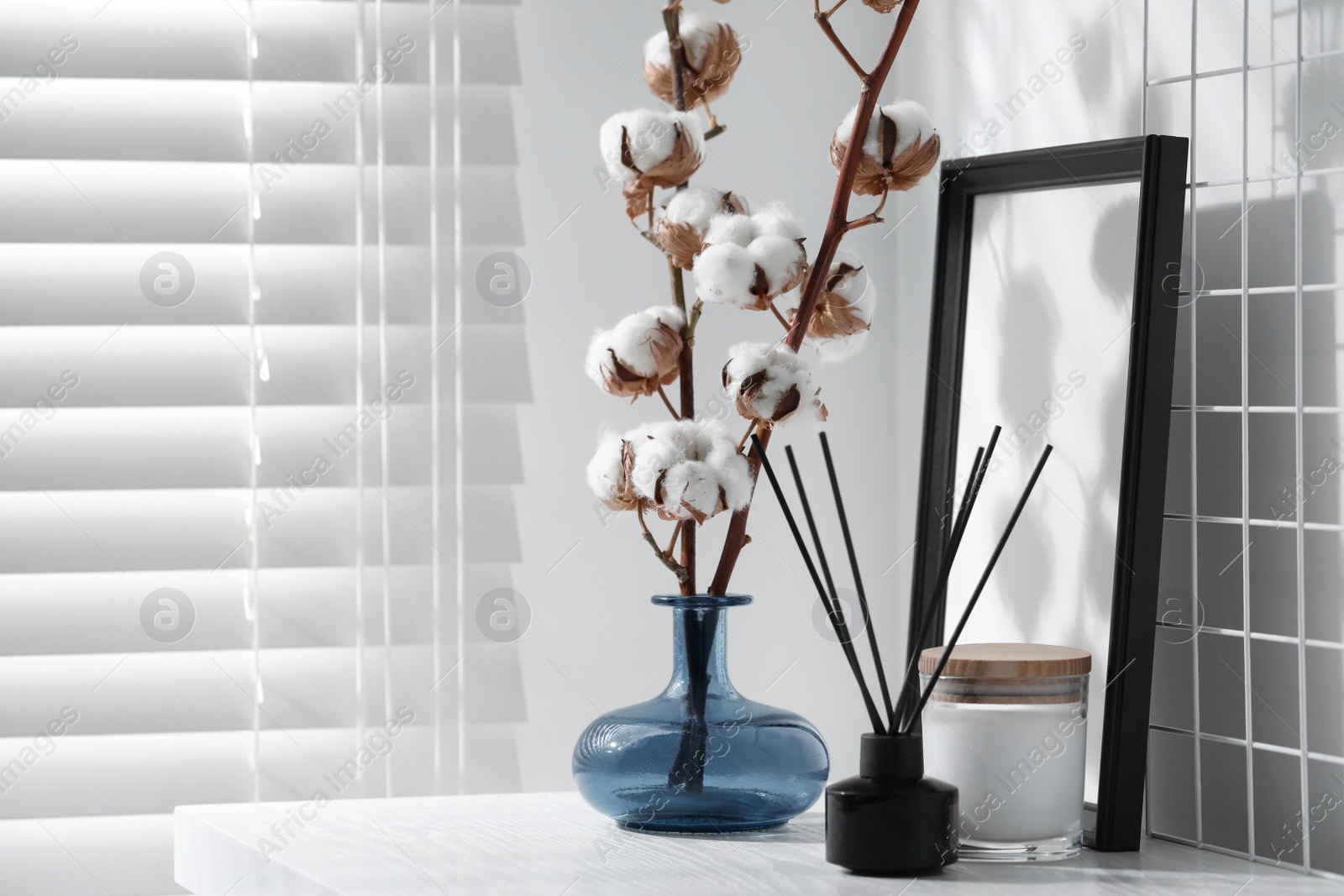 Photo of Reed diffuser, candle and cotton branches with fluffy flowers on white wooden table indoors. Space for text