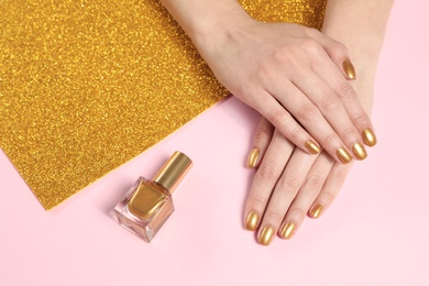 Photo of Woman showing manicured hands with golden nail polish on color background, closeup