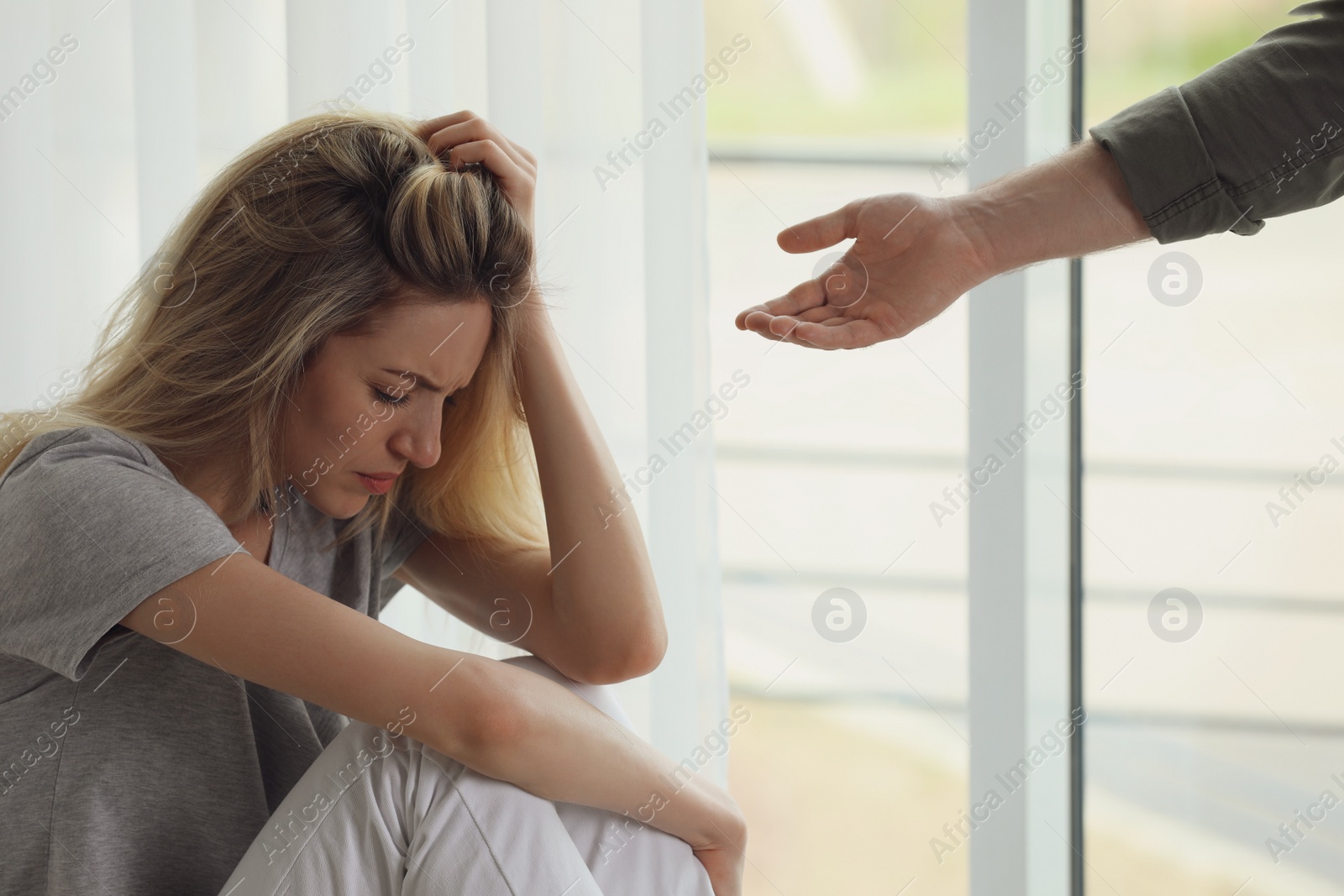 Photo of Man offering hand to depressed woman indoors