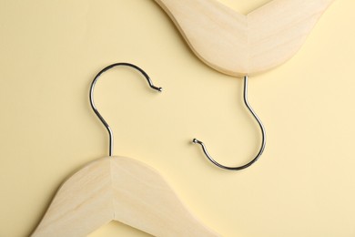 Wooden hangers on pale yellow background, flat lay
