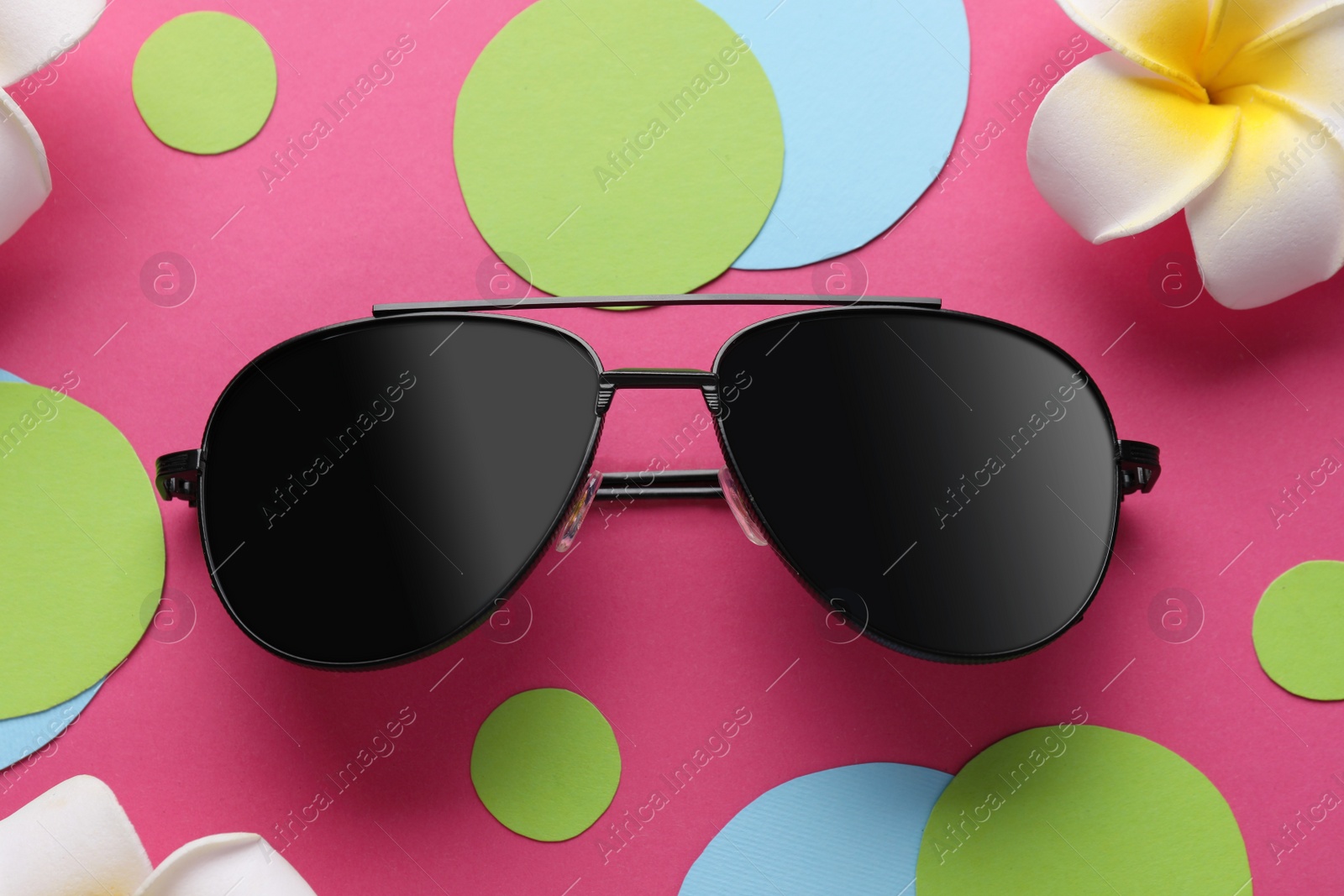 Photo of Stylish sunglasses and flowers on color background, flat lay
