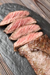 Photo of Pieces of delicious grilled beef meat on wooden table, closeup