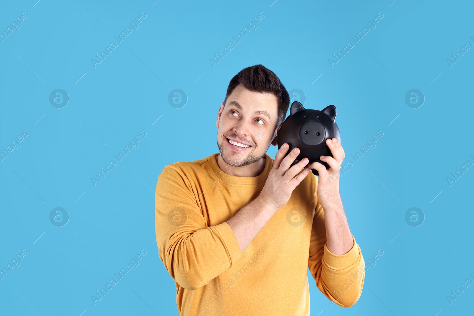 Photo of Man with piggy bank on color background