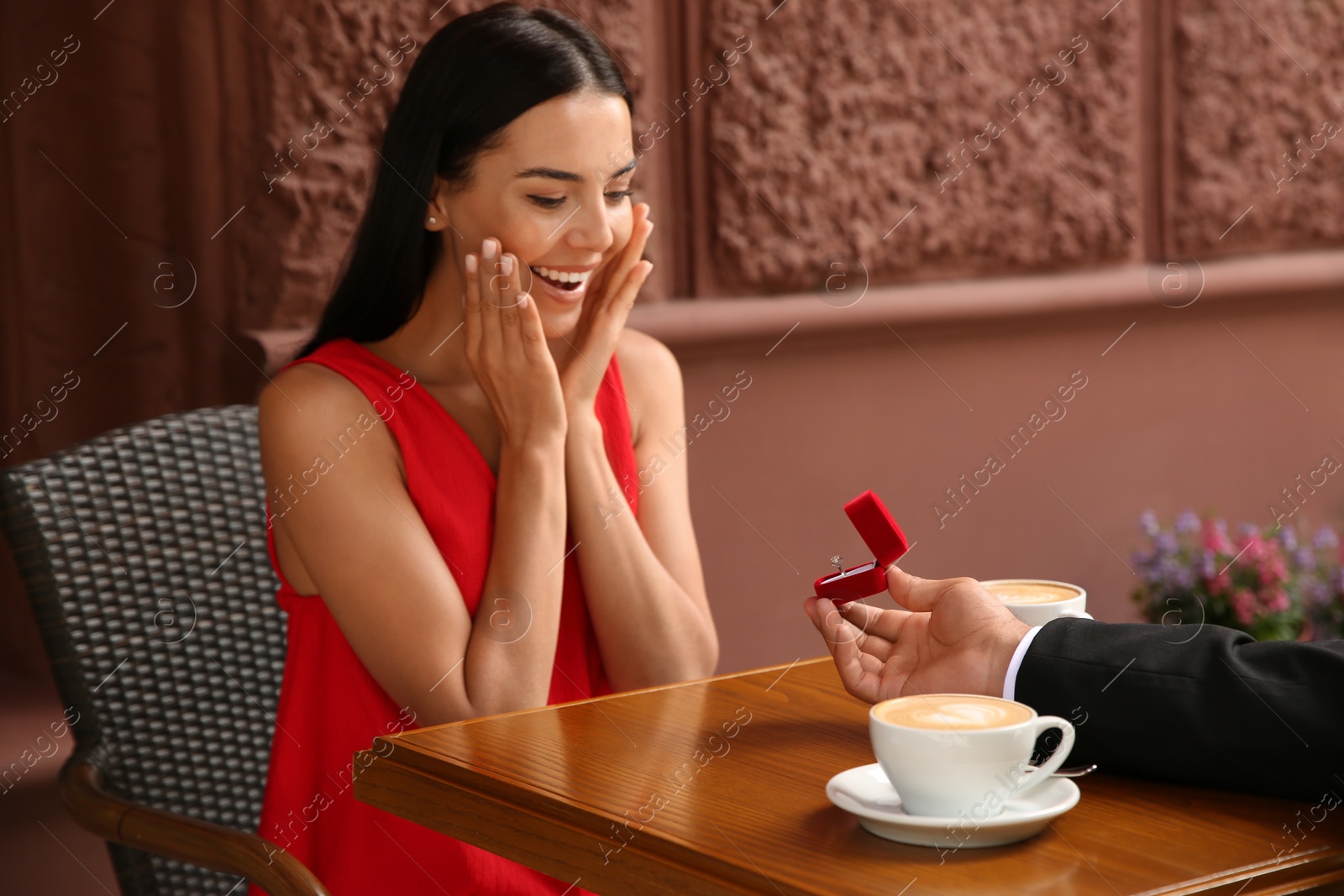 Photo of Man with engagement ring making proposal to his girlfriend in outdoor cafe