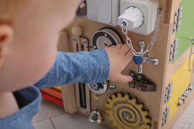 Little child playing with busy board cube on floor, closeup