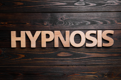 Word HYPNOSIS on wooden background, flat lay