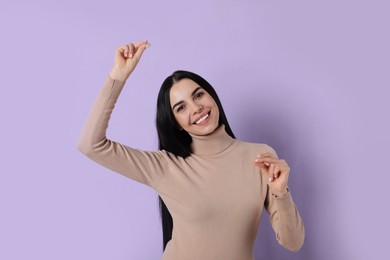 Photo of Young woman snapping fingers on violet background