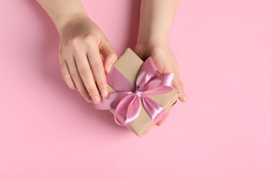Woman with gift box on pink background, top view